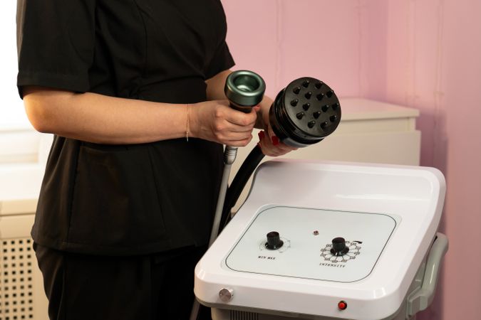 Spa therapist demonstrates two handpieces for body contouring machine