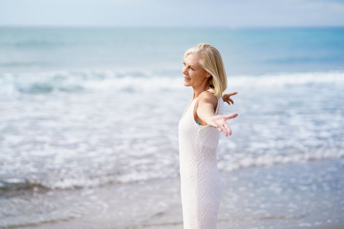 Side view of mature woman opening her arms on a beautiful beach