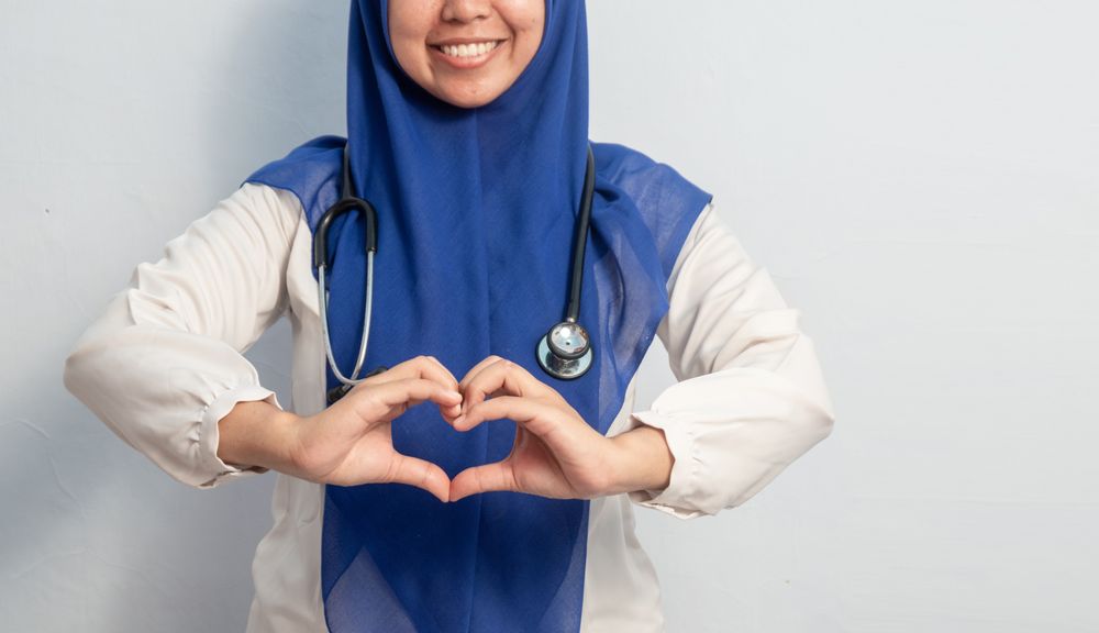 Muslim Female asian doctor or nurse with hand in love or heart symbol.
