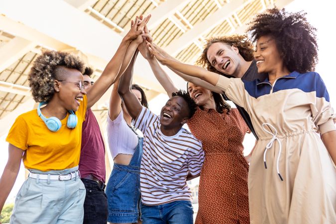 Group of multi-ethnic adult friends joining hands outdoors