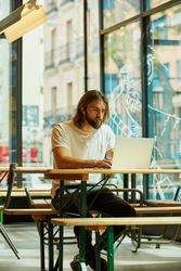 man sitting at table and typing on laptop