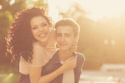Happy teenage girl on her boyfriend’s back in piggy back outside, copy space
