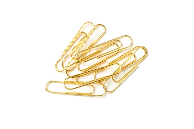 Gold paper clips isolated on studio background, closeup