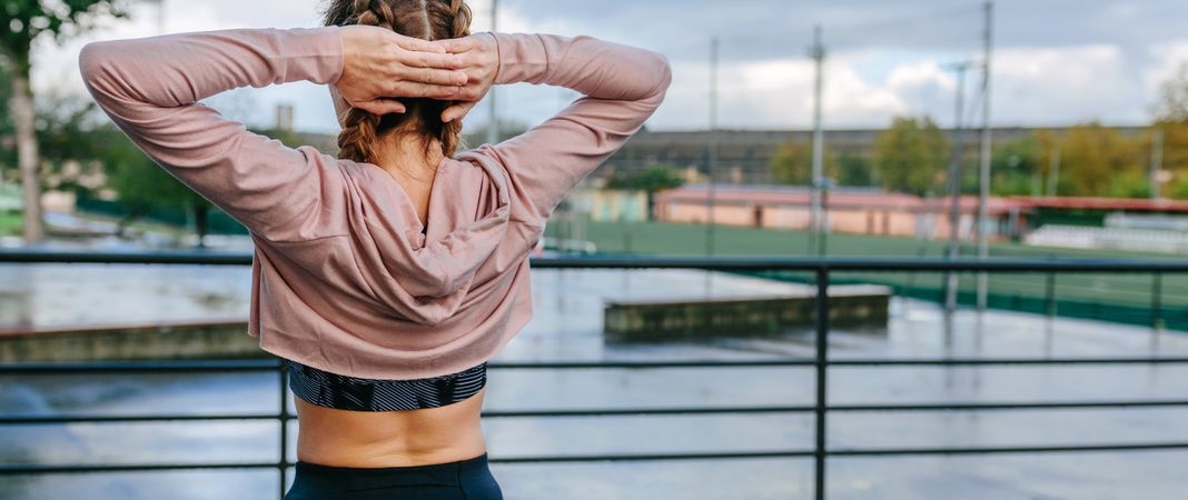Young sportswoman stretching neck and shoulders outdoors