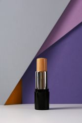 Concealer stick on modern background with geometric shapes.