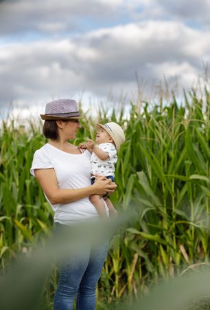 Adorable mother and child on hand enjoying and laughing in field