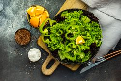 Top view of green fresh salad on concrete background served with flax seed, salt and lemon