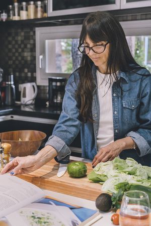 woman reading recipe while preparing food in the kitchen. Vertical shot