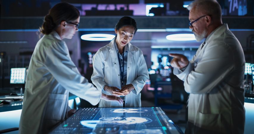 Modern Hospital Medical Cancer Research Center: Diverse Scientists Gathered Around Interactive Touch Screen Table With CT Scans Of Brain On Display.
