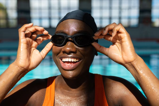 Black female swimmer smiling while she adjusts her goggles