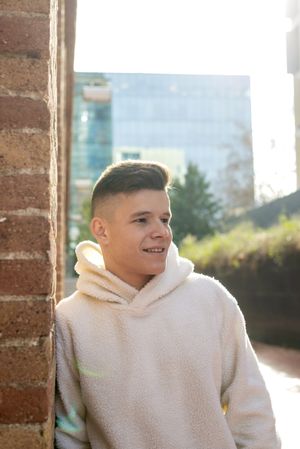 Portrait of smiling young man leaning against brick wall in the sunshine