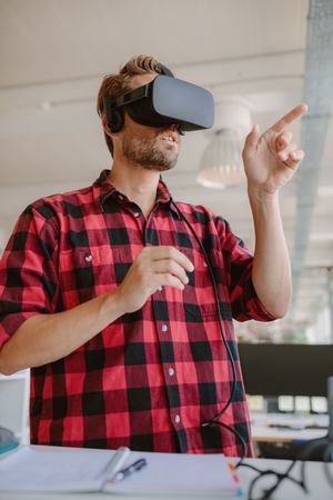 Young man wearing virtual reality glasses and gesturing