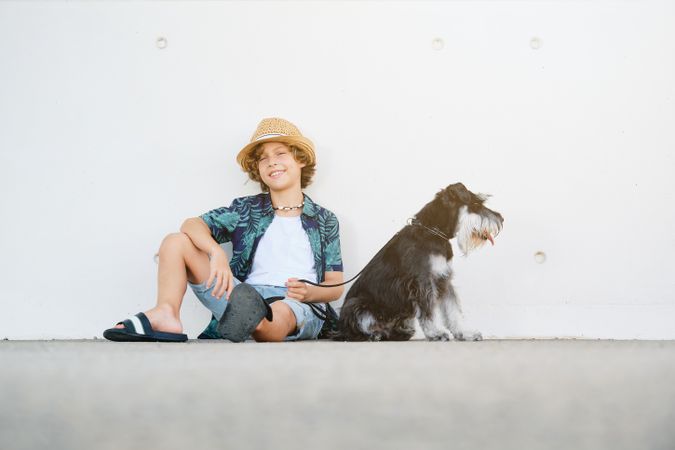 Smiling child with dog sitting against wall
