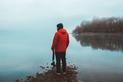 Tourist on empty lake shore in fog