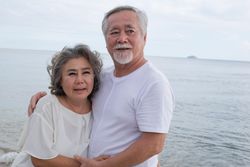 Mature Asian couple holding each other at the beach