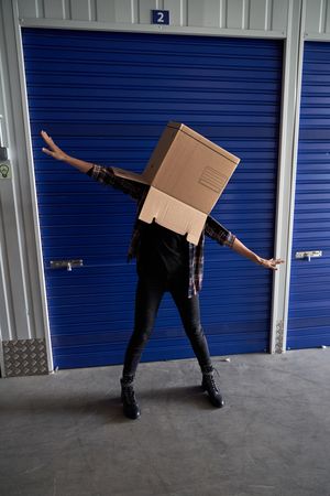 Faceless carefree person with box on head
