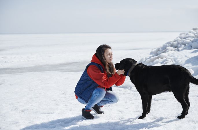 Young adult woman outdoors having fun with her dog in the snow