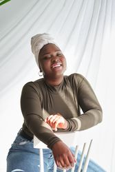 Confident Black female model in turban sitting on white chair
