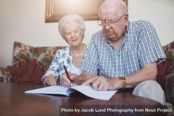Indoor shot of older couple at home signing paperwork together 0yN6a5