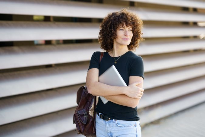 Confident Young Woman Working on Her Laptop Against a Modern, Stylish Background Setup