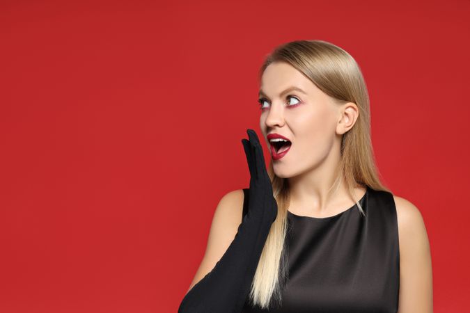 A young woman in a zombie costume, on the occasion of the Halloween holiday, on a red background.