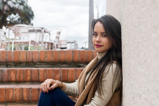 Woman sitting leaning on wall and looking at camera