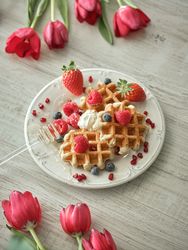 Sweet waffles on table with tulips