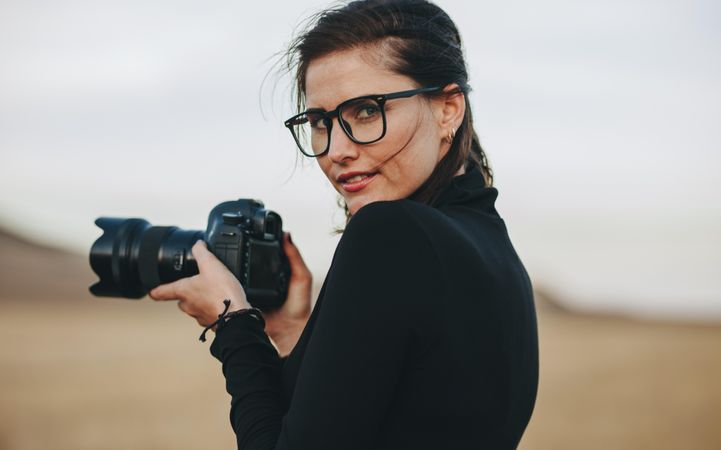 Portrait of photographer looking over her shoulder holding dslr