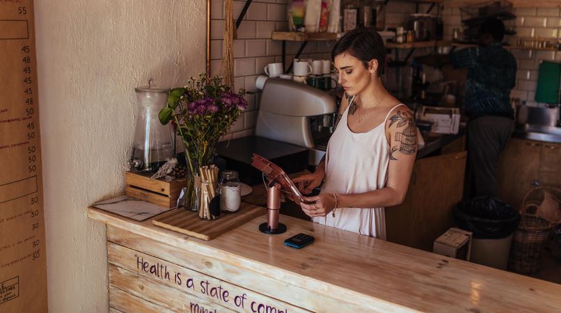 Woman standing at the billing counter of her coffee shop