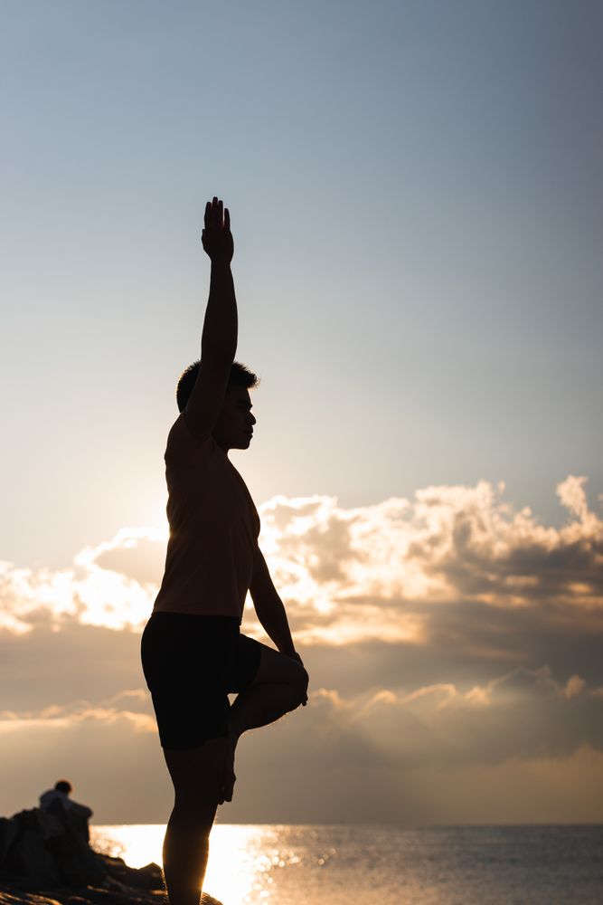 Man practicing yoga asana at sunset