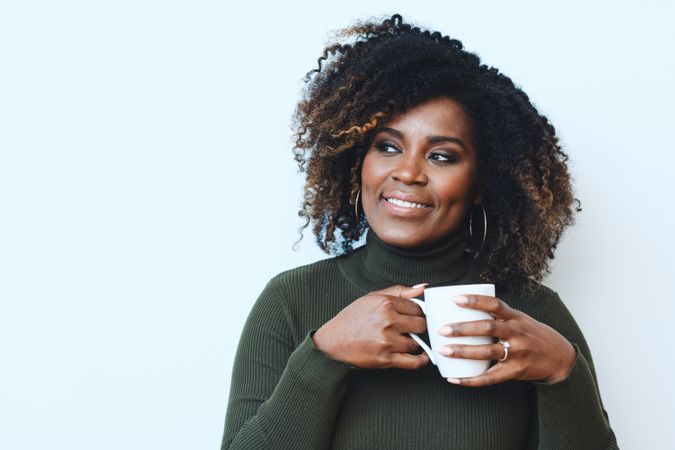 Content Black woman holding a cup of coffee while deep in thought