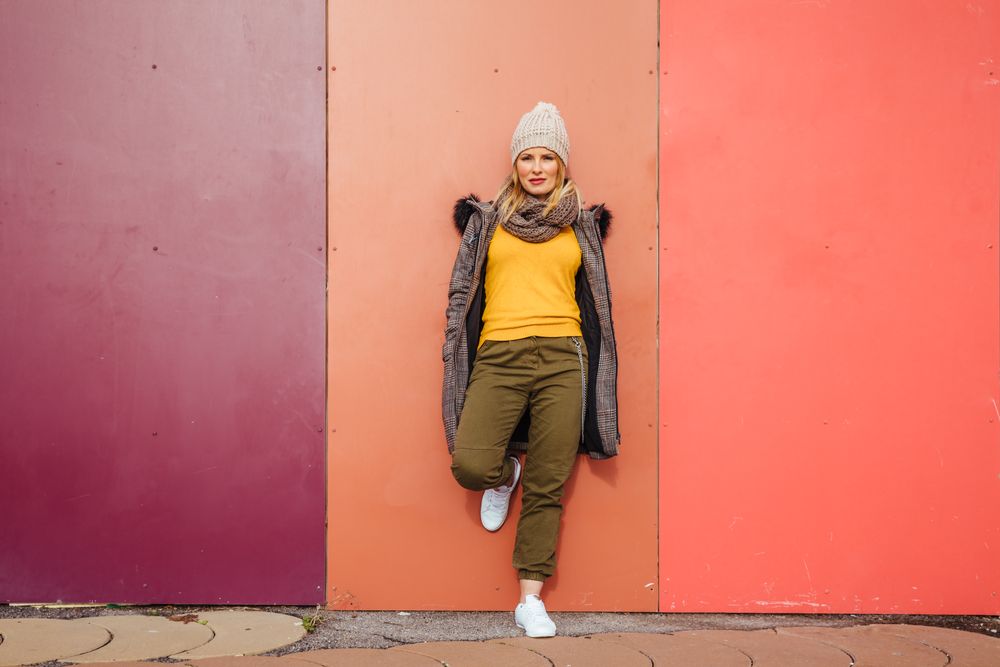 Blonde woman leaning on a colorful wall