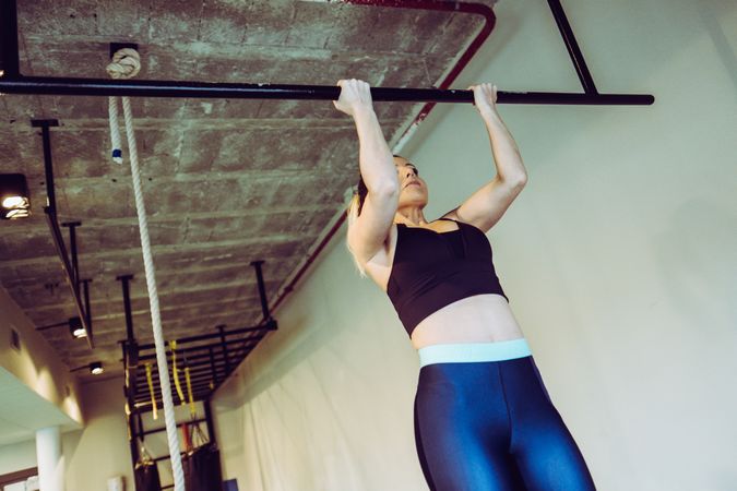 Young woman doing pull ups in gym