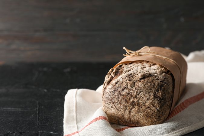 Rye bread on kitchen towel on table against wooden background, space for text and closeup