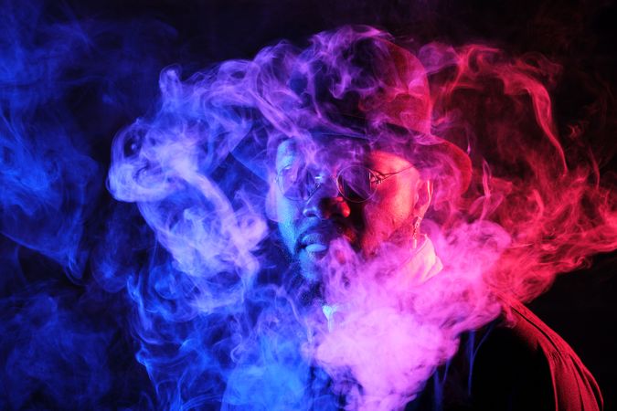 Stylish Black man in smoke in neon light
