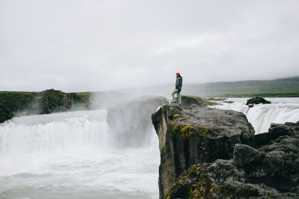 Man on cliff over waterfall, landscape