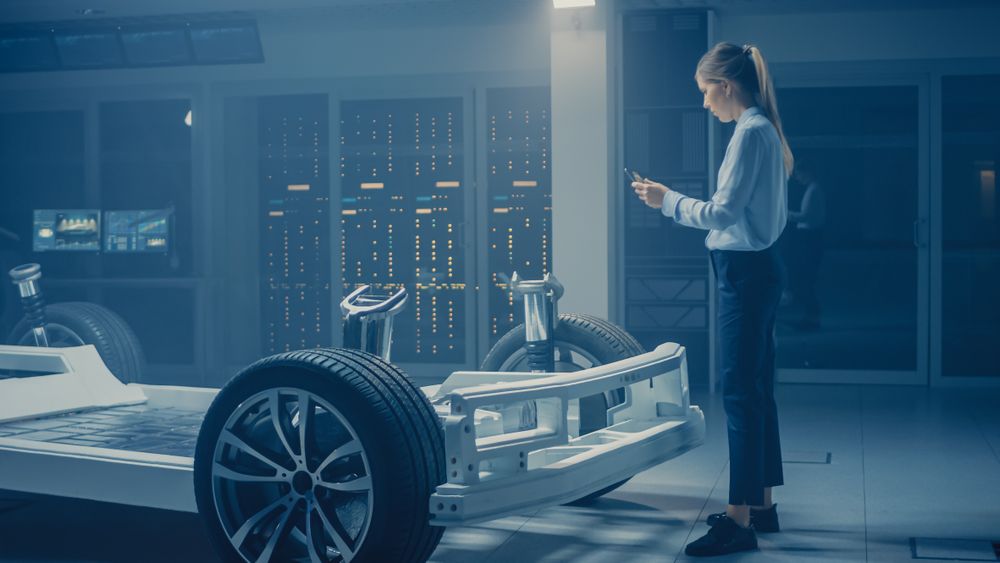 Automobile Engineer Working on Electric Car Chassis Platform, Using Tablet Computer Augmented Reality with 3D CAD Software Modelling.