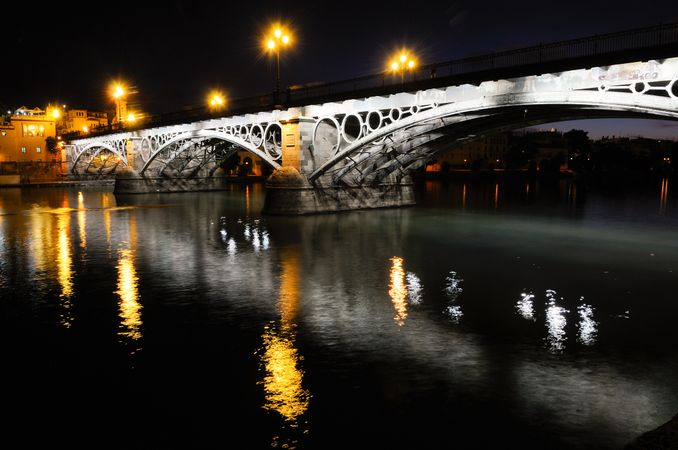 Triana Bridge over Guadalquivir river at sunset with river reflections