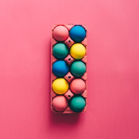 Colorful Easter eggs in box on pink background
