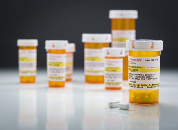 Medicine Bottles and Pills on Reflective Surface With Grey Background