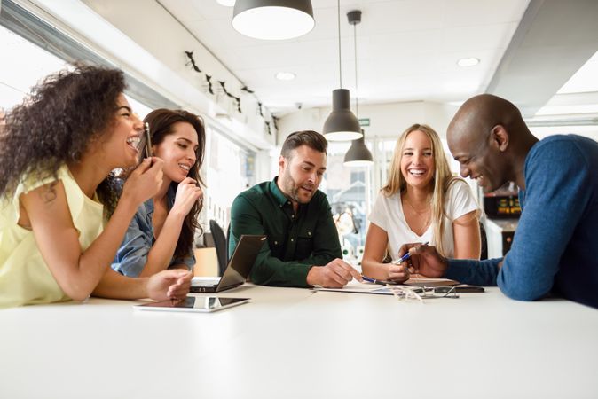 Group of people sharing a joke at a meeting around a table to work on project