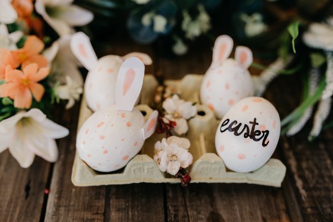 Easter eggs with rabbit ears painted by children in an egg cup with flowers