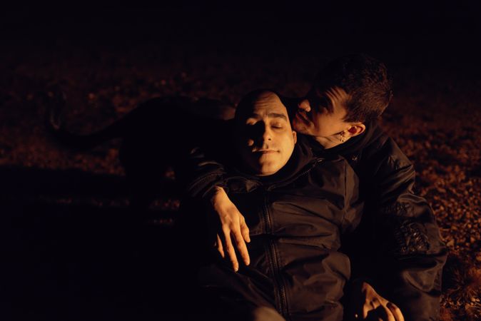 Men hugging and sitting on ground on field at night