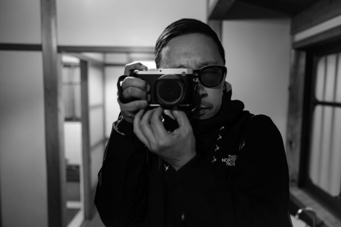 Grayscale photo of man using a camera
