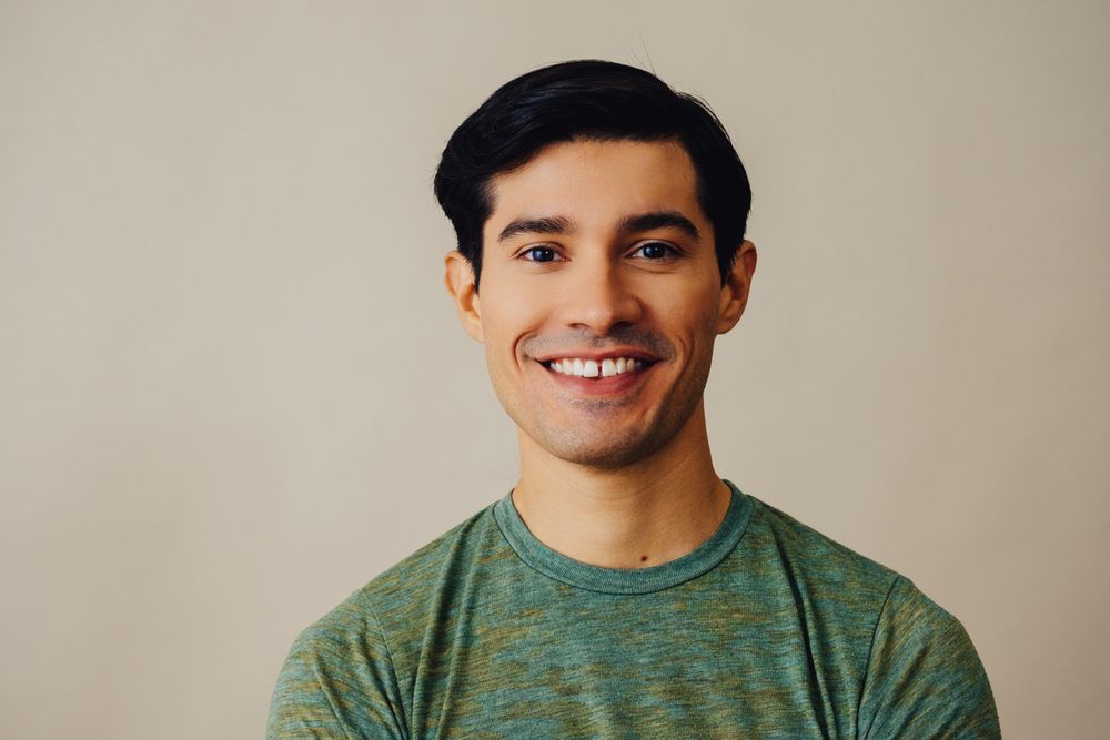 Portrait of happy Hispanic male in neutral room, copy space