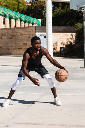 Black man playing basketball on sports ground