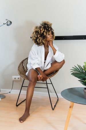 Black woman sitting in round chair in light room