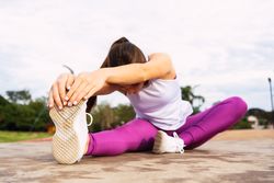 Young sportswoman stretching legs while exercising