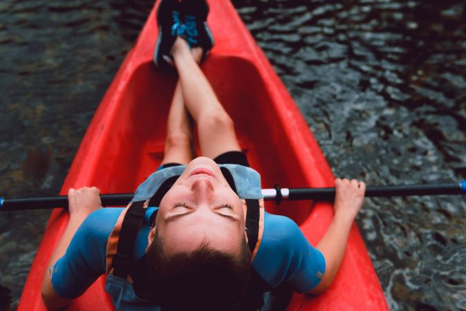Female kayaking with paddle in raised hands