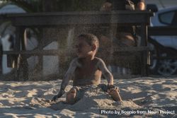 Young boy playing with sand on the beach 0ydVqb